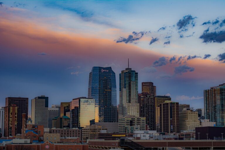 Stunning view of Denver's cityscape with skyscrapers under a colorful sunset sky.