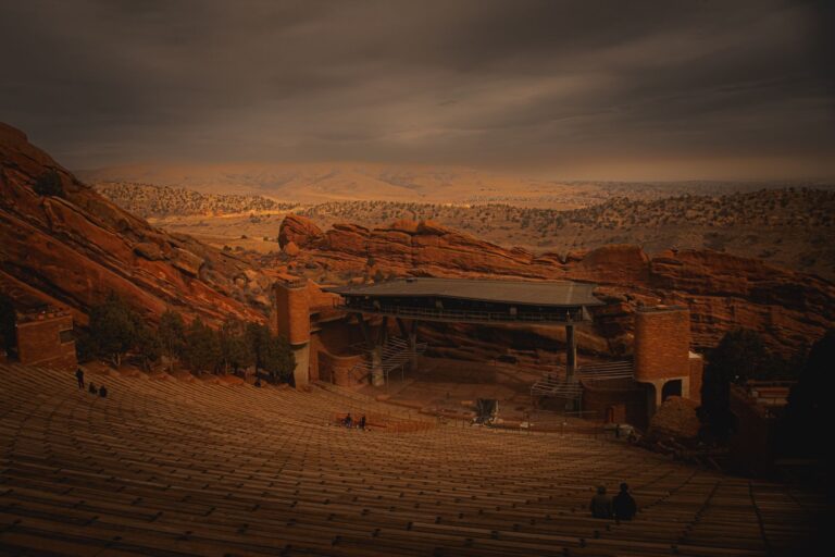 Red Rocks Amphitheatre amidst dramatic reddish rocks under an evening sky.