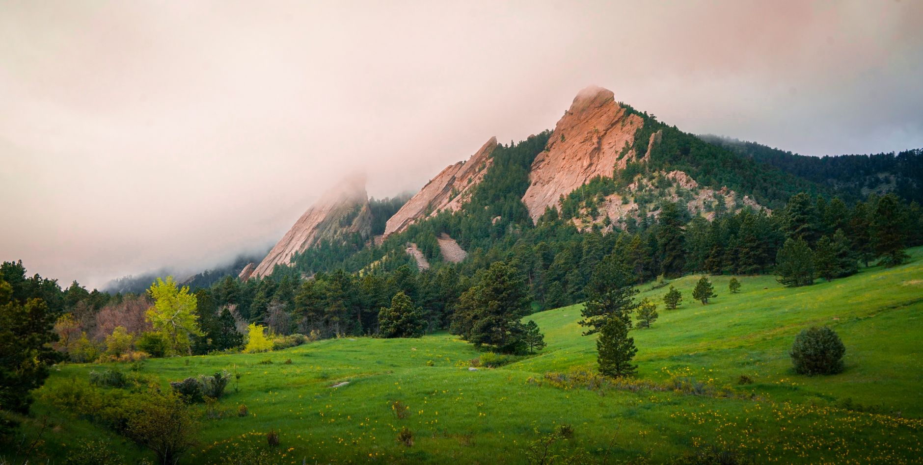 Misty morning view of the Flatirons in Boulder, Colorado showcasing lush greenery.